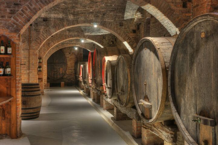 Bodega de ladrillo abovedada con hileras de toneles de madera envejeciendo