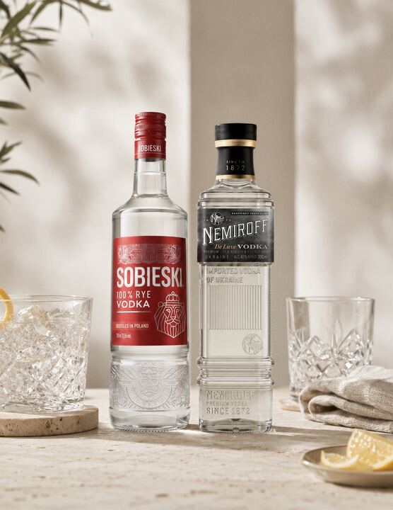 Vodka Nemiroff De Luxe junto a Sobieski, con vasos tallados y limón sobre piedra clara